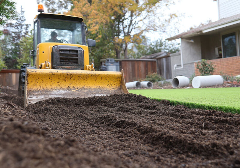 AdobeStock_1303456562 Landscaping tractor leveling dirt in residential yard